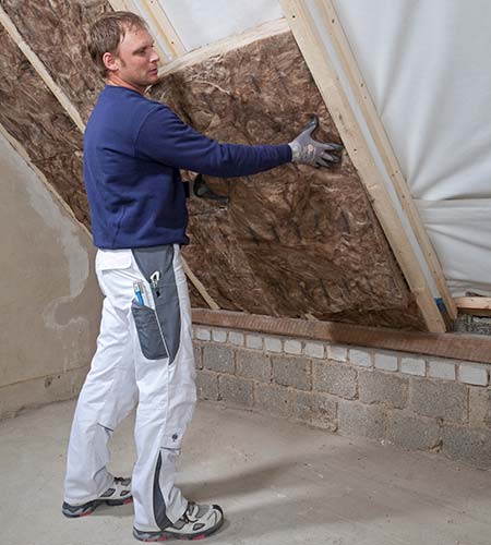 Handwerker verlegt die Zwischensparrendämmung Knauf Insulation aus Glaswolle Handwerker verlegt die Zwischensparrendämmung Knauf Insulation aus Glaswolle